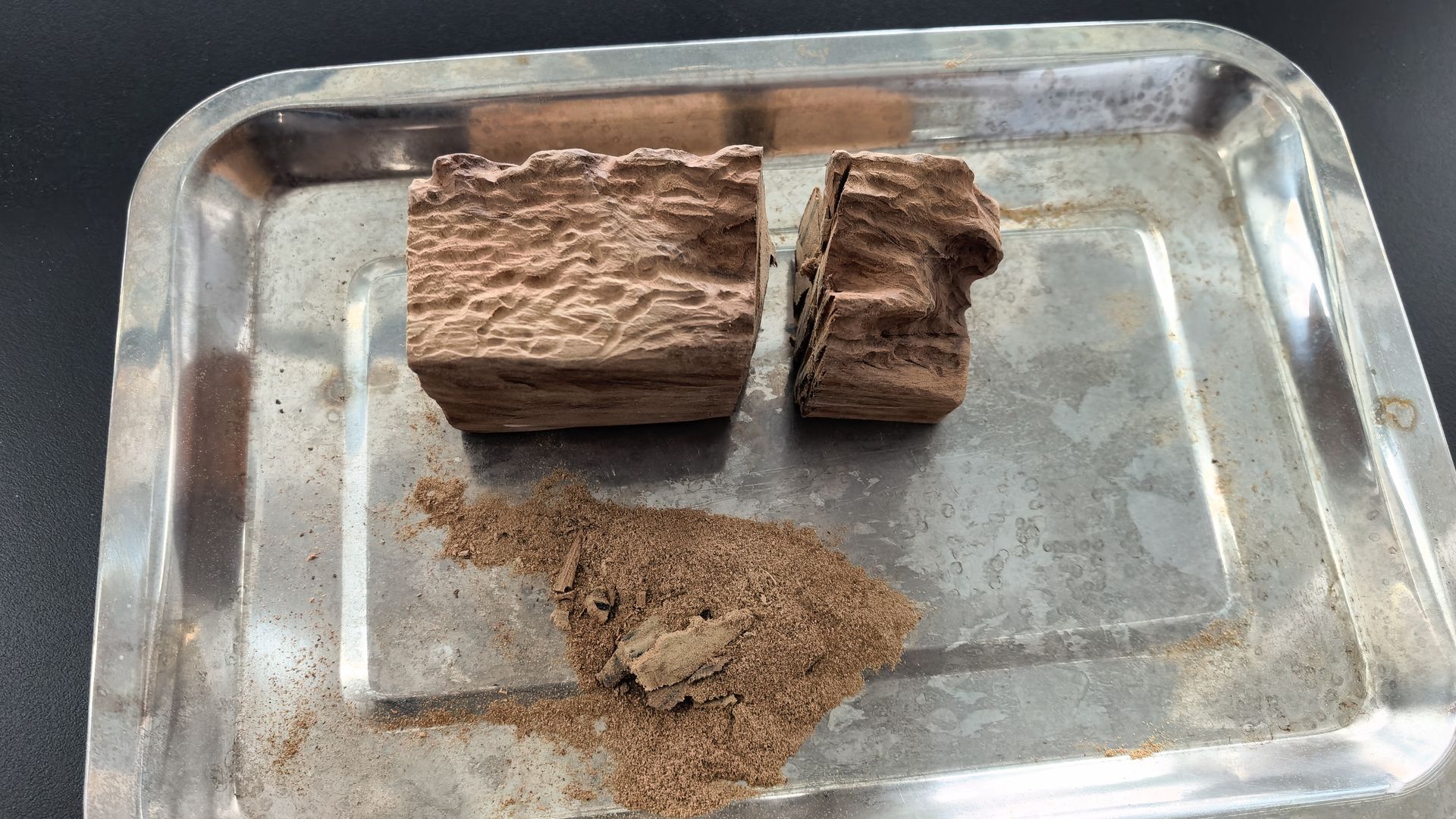 Antique camphor wood being ground into powder in mortar for carbon extraction preparation