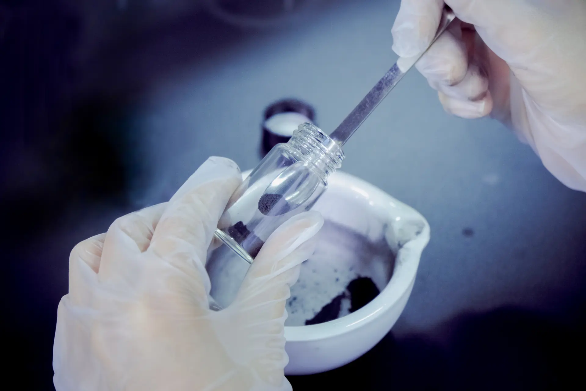 Carbon powder being transferred into a vial using precision tweezers — laboratory carbon extraction process