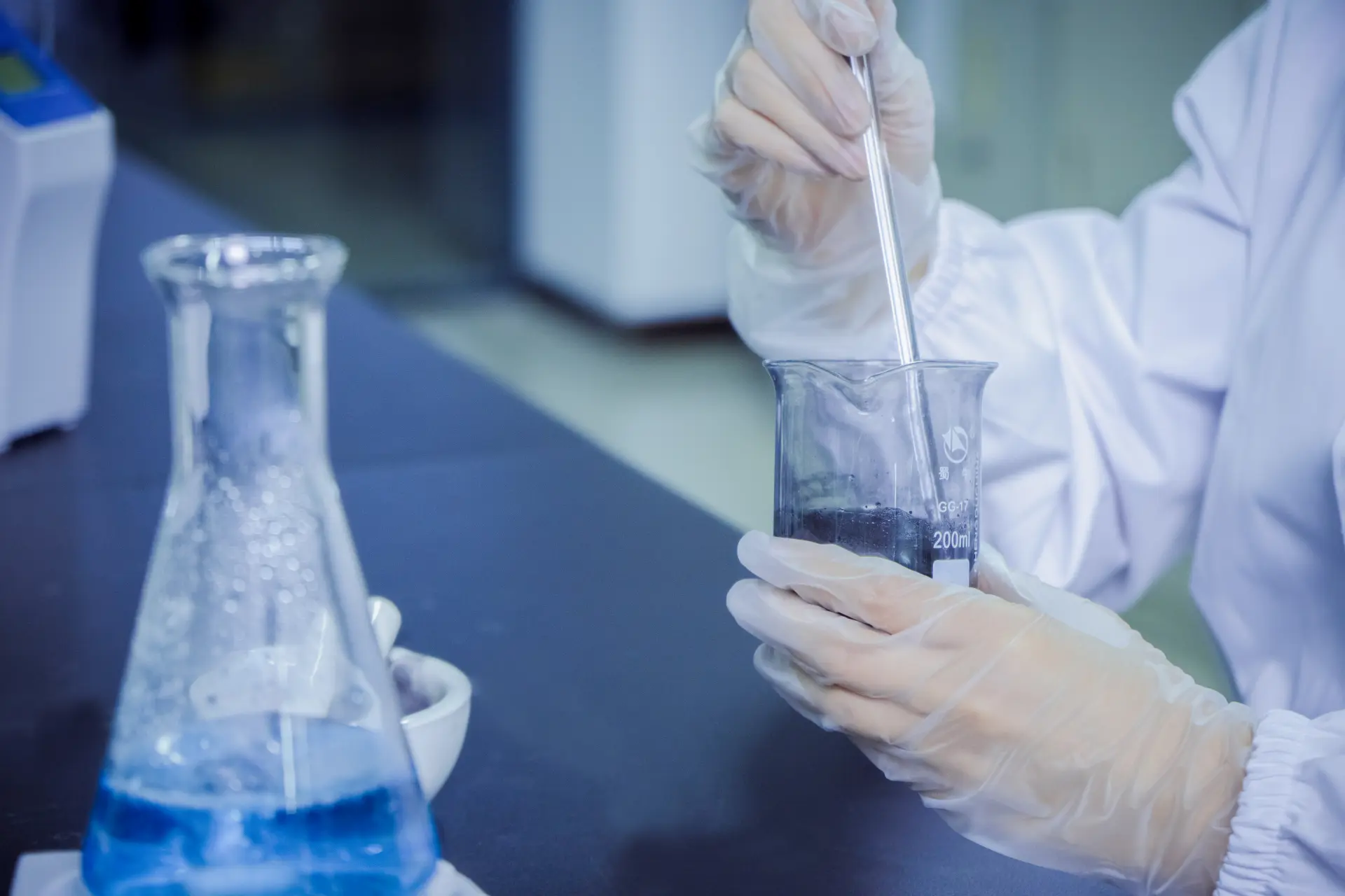 Laboratory technician performing carbon purification chemical reaction — precision reagent mixing in analytical glassware