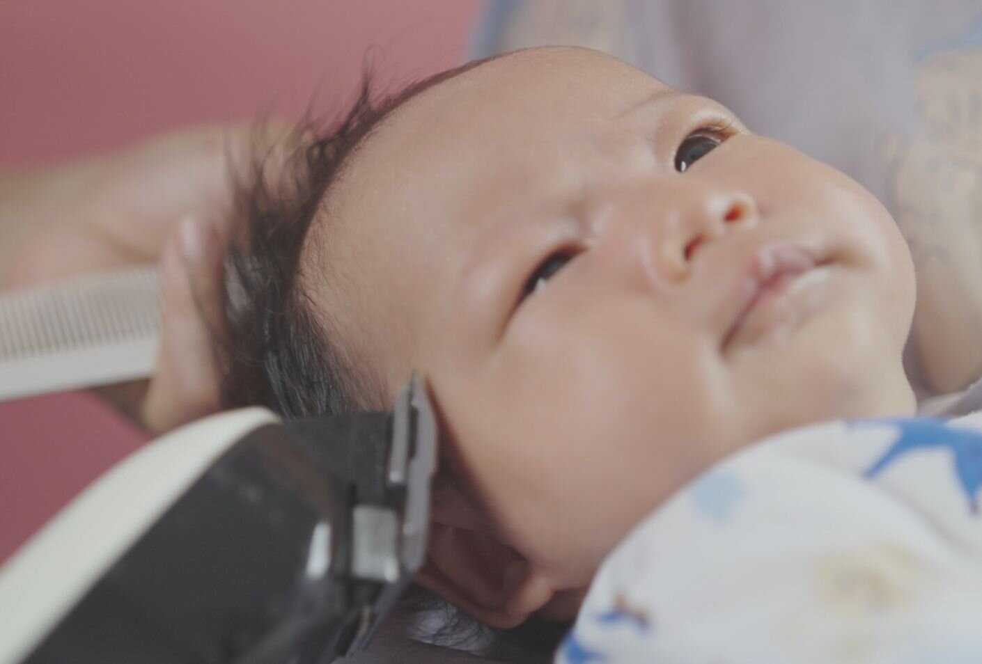 Profile view of baby hair being trimmed during the traditional first haircut