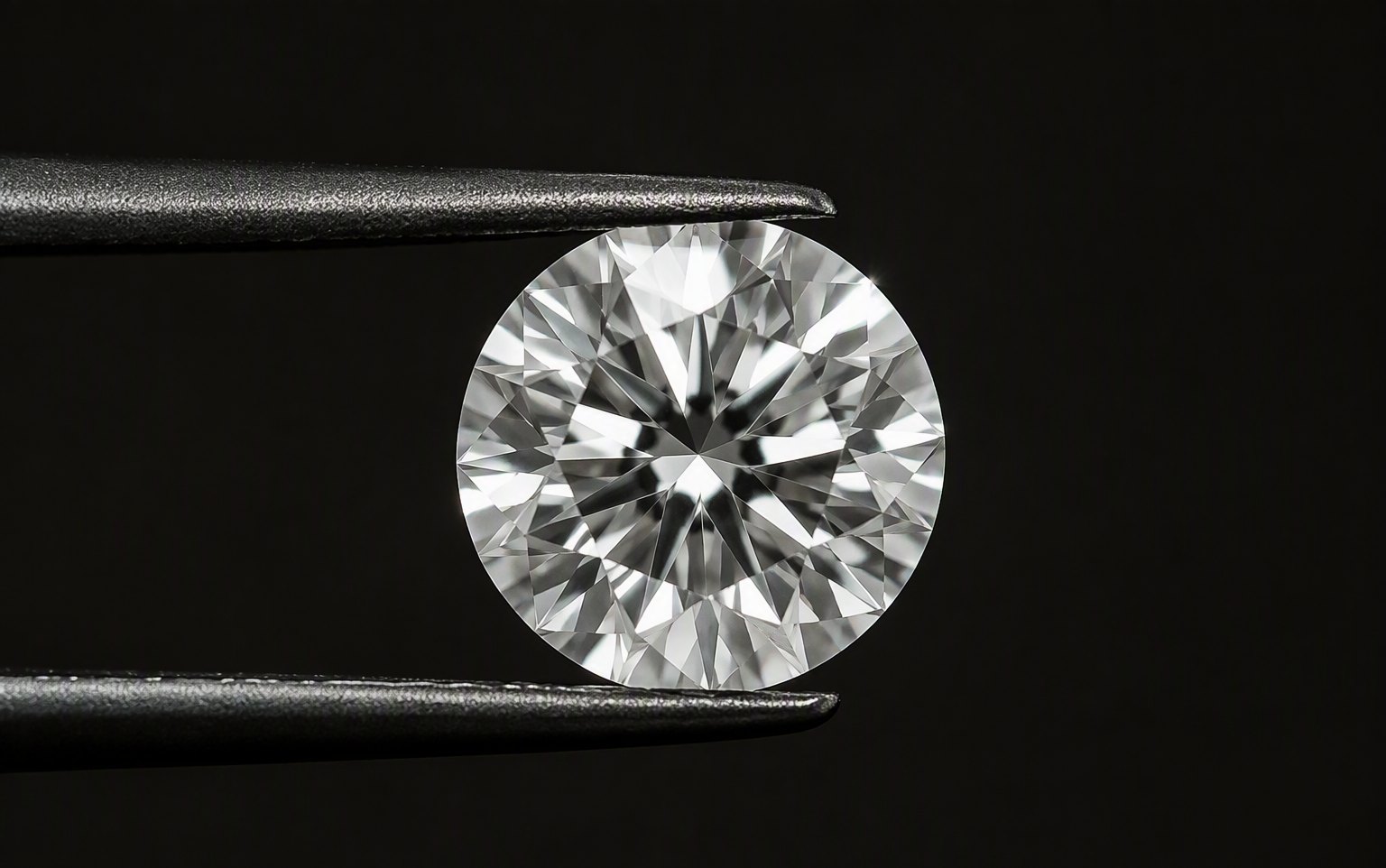 Colorless round brilliant memorial diamond in tweezers, macro