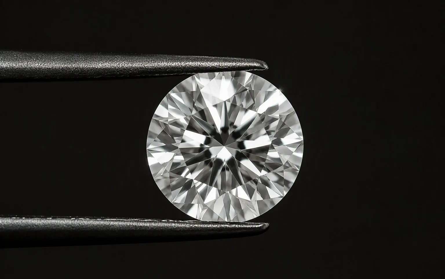 Colorless round brilliant memorial diamond in tweezers, macro